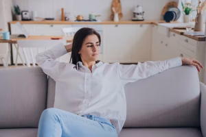 young woman in a white shirt and jeans sitting on a sofa